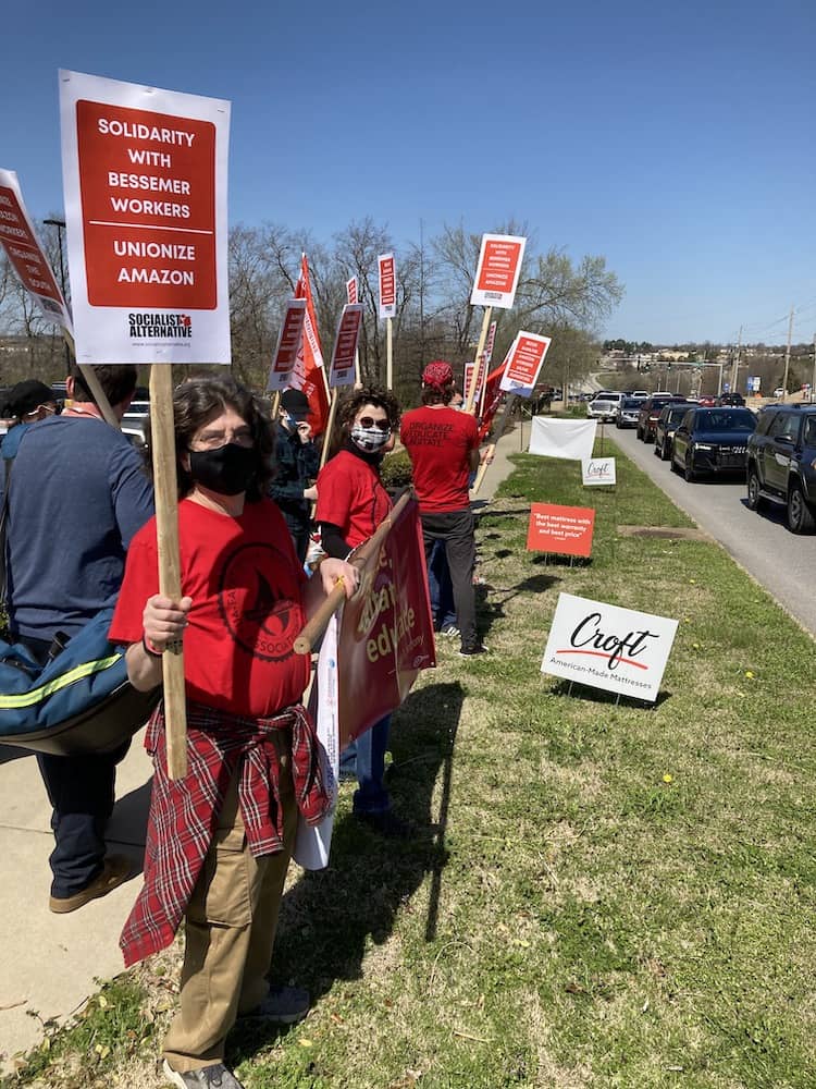 Red-shirted 965 members Ben Pollock, Tricia Starks and Geoff Brock join the Solidarity with Amazon Workers rally March 20, 2021, outside the Fayetteville Whole Foods Market.